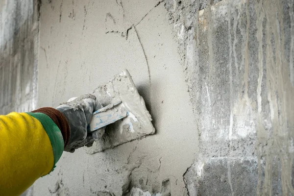 hand a worker plastering cement wall in construction site