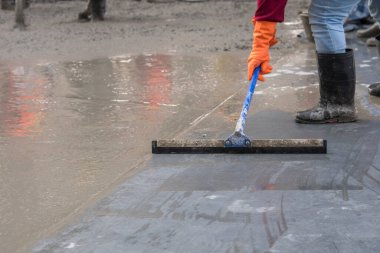 İnşaat işçisi beton zeminin tepesine ıslak beton döküyor. Yeni inşaat alanı.