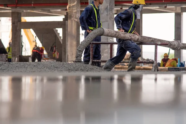 建設労働者建設現場及び土木技術者の建築物の商業コンクリート床にコンクリートを流し込む — ストック写真