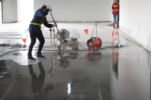 Construction worker painting epoxy flooring or floor hardener