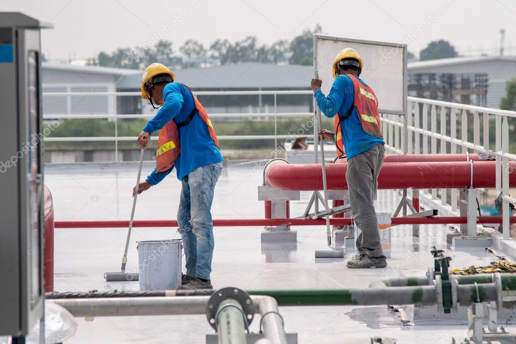 Construction worker coating epoxy paint at roof slab for water proof protection