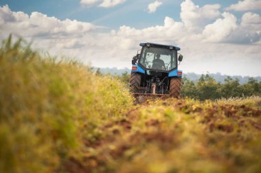 Çiftlik arazisinde çalışan mavi bir traktör