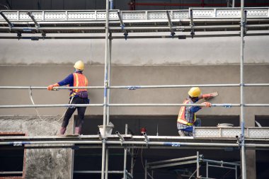 İnşaat işçisi çimento sıva iskele, güvenlik üniforması.