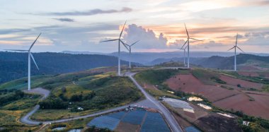 Rüzgâr türbininden hava manzarası. Tarlada inşaat, dağda çayır. Güzel mavi gökyüzü güneşli.