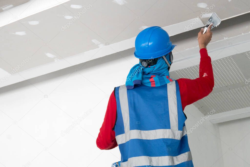 Construction worker plastering ceiling work