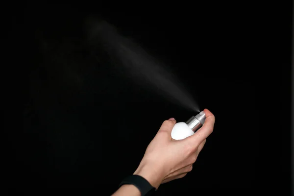 antiseptic hand spray in the air on a black background to protect against coronavirus, free space for text , close-up