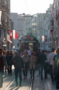 13 Aralık 2019 Taksim / Türkiye Tramvayı ve Istiklal Caddesi 'nden geçen insanlar. Güneşe karşı