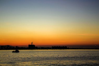 Denizin ortasında, gemiler ve güneşin batısında.