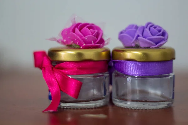 Küçük süslü kapaklı kavanoz şişeleri. Kurdele etrafına dolanmış.