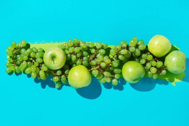 Taze yeşil üzümler ve mavi arka planda elmalar. 