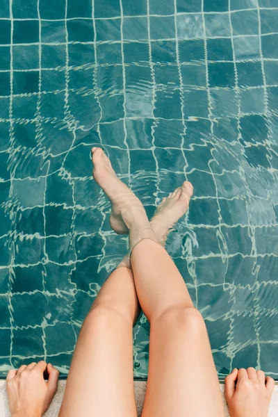 Female legs in a cold swimming pool shot from above, summer lifestyle concept