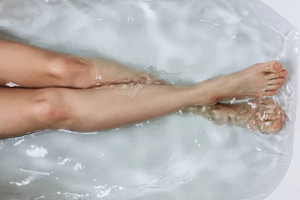 Temiz suyla banyo küvetinde kadın bacakları, kişisel bakım konsepti.