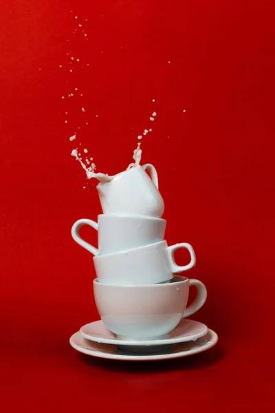 上にクリーム入りの様々なカップとソーサーのスタックと内部のスプラッシュ 選択的な焦点 — ストック写真