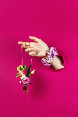 Kadının elini, gümüş zincirli, seçici bir odak noktasında, elinde buket olan yırtık bir kağıt şişeyle yakınlaştırmak.