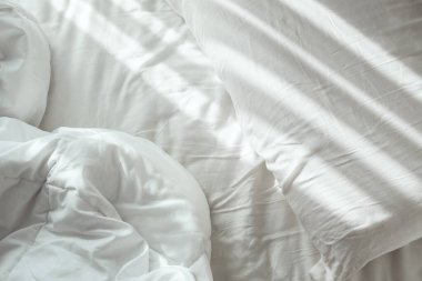 Yastığın üzerinde parlak güneş ışığı olan boş beyaz çarşaflar.