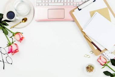 Pembe dizüstü bilgisayarlı, mumlu, güllü, gözlüklü ve beyaz üzerine diğer aksesuarlarla süslü düz çerçeve düzenleme. Kadınsal iş modeli, kopyalama alanı
