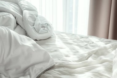 Beyaz buruşuk çarşaflı yatak ve sabah güneşinde battaniye, seçici bir odak