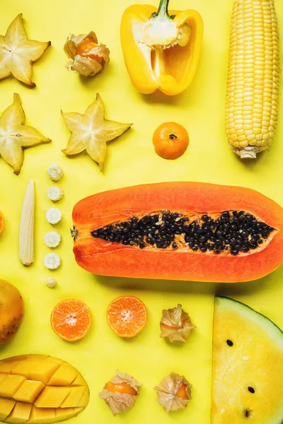 Flatlay of various yellow and orange fruits and vegetables knolled together