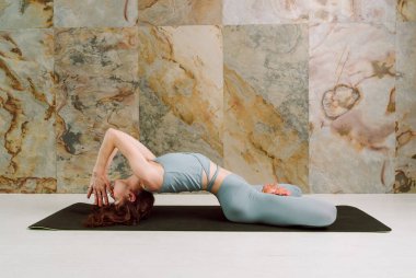 Genç Yogini, Matsyasana pozu veriyor. Pastel mavisi tozluklarla ve seçici bir odak noktasıyla.