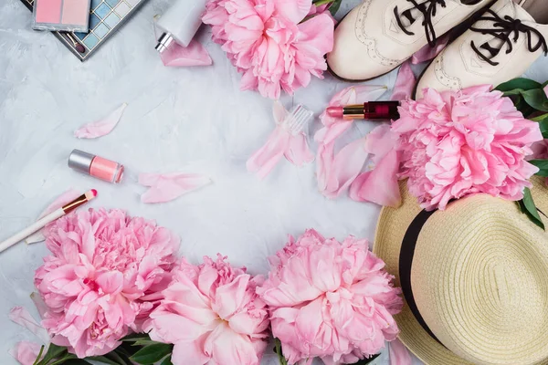 Feminine flatlay mockup with hat, pink peonies, cosmetics and white brogue shoes on cement background with copyspace