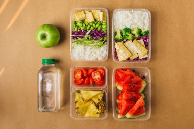 İki sağlıklı Asya usulü vejetaryen öğle yemeği. Bento kutularında pilav, kızarmış tofu, edamame fasulyesi ve meyve.