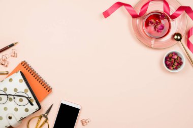 Pastel arka planda çeşitli sabit aksesuarlar bir fincan çay ve siyah telif alanı olan akıllı telefon, kadınsı iş modeli