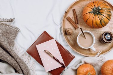 Ahşap tepsiyle, bir fincan kahveyle, kakaoyla, mumla, balkabağıyla, beyaz çarşaflarla ve battaniyelerle kaplı defterlerle.