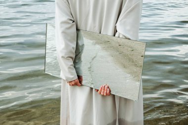 Yakından bakınca, mavi elbiseli bir kadının elinde plajda yansıyan bir ayna, seçici.
