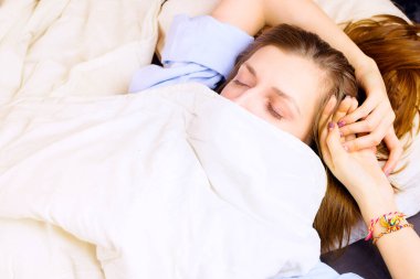 Genç ve güzel bir kadın, yüzü battaniyeyle örtülmüş, gözleri kapalı yatıyordu. Seçici odaklanma, sabah ya da gece uyku konsepti.