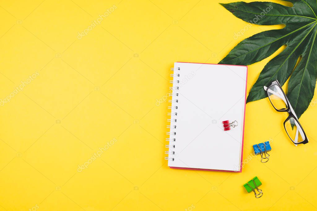 Business flatlay with tropical leaves and business accessories: planner, glasses, clips, etc. Copyspace