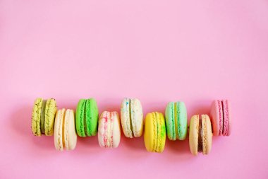 Pembe bir arka plan üzerinde renkli macarons satır. Üstten görünüm. Kopya alanı.