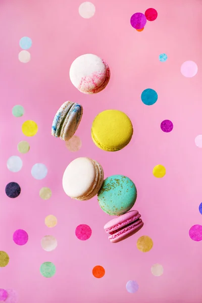 Macarons français doux et colorés volent en mouvement avec des confettis . — Photo