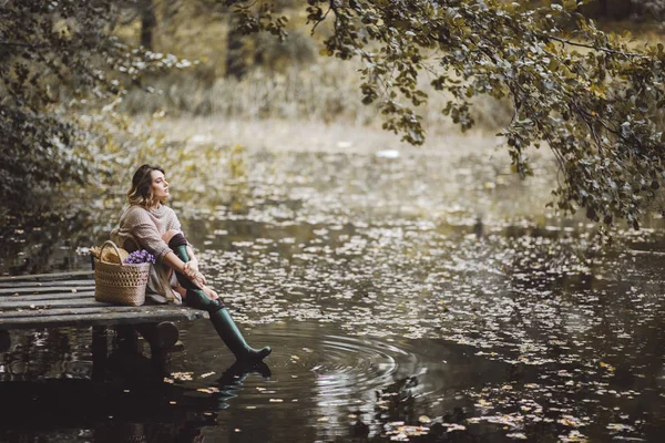 Bella donna sognante seduta sul molo vicino al lago . — Foto Stock