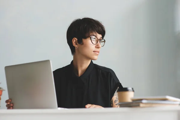 Nachdenkliche Geschäftsfrau arbeitet im Büro mit Laptop — Stockfoto