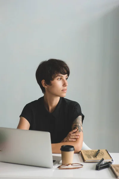 Nachdenkliche junge Geschäftsfrau mit Laptop im Büro — Stockfoto