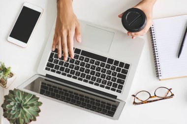 Laptop ile çalışan genç kadın beyaz masanın üzerine yerleştirilen