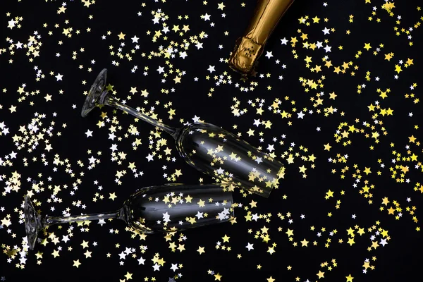 Due bicchieri e una bottiglia di champagne su sfondo di stelle dorate Foto Stock Royalty Free