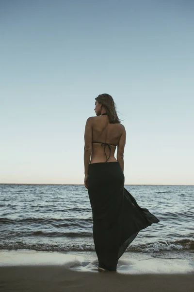 Vue de dos silhouette de belle femme debout le long de la plage avec la mer sur fond . — Photo