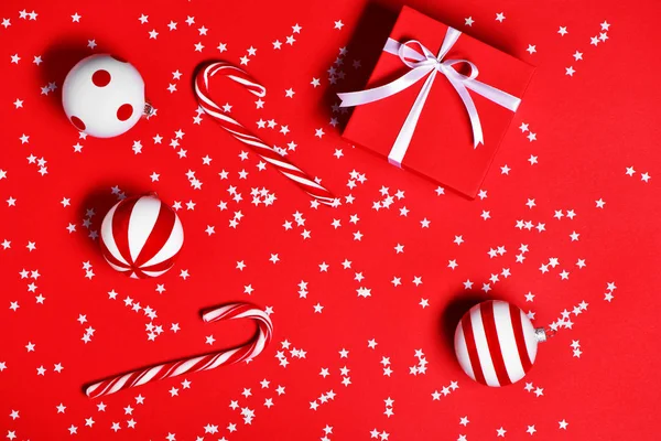 Weihnachtsdekoration mit Zuckerstangen, Geschenkbox und Weihnachtsspielzeug auf rotem Hintergrund. — Stockfoto