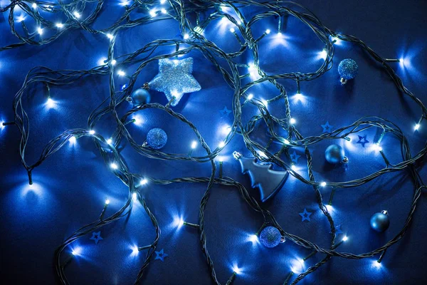 Γιρλάντα λαμπτήρες με μπλε φωτισμός με χριστουγεννιάτικα παιχνίδια σε μπλε φόντο — Φωτογραφία Αρχείου