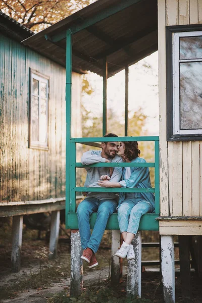 Linda pareja romántica sentada en el porche de la cabaña de madera . — Foto de Stock