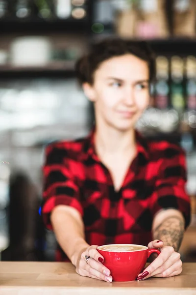 Beskuren bild av vackra barista holding kopp kaffe vid disken i kaféet — Stockfoto