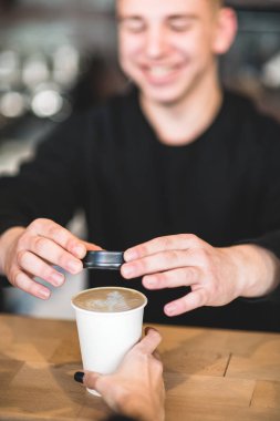 Barista, kahve dükkanının tezgahına götürmek için kağıt fincan kahve tutuyor