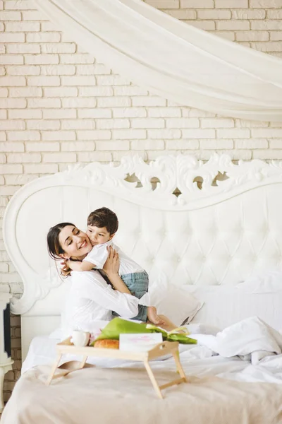 Μητέρα με μικρό γιο περνούν ευτυχισμένη οικογενειακή ώρα στο σπίτι χαμογελώντας και αγκαλιάζοντας στο κρεβάτι — Φωτογραφία Αρχείου