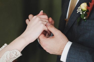 Nişanlanmış çiftin alyansla el ele tutuşuğu yakın çekim