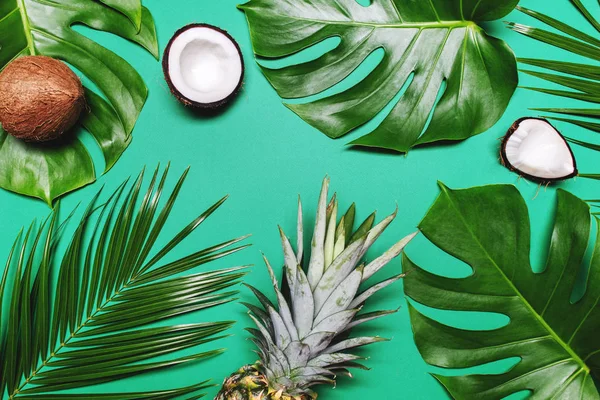 Abacaxi, cocos maduros, palma tropical e folhas de monstera verdes sobre fundo verde . — Fotografia de Stock
