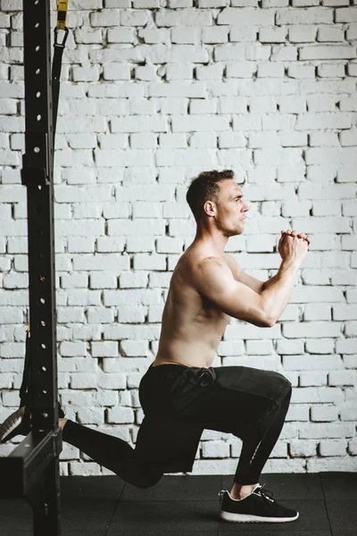 Athletic człowiek z fit muskularne ciało praktykujących kuca w siłowni. — Zdjęcie stockowe