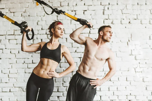 Spor salonunda Trx egzersiz yapıyor Atletik adam ve kadın.