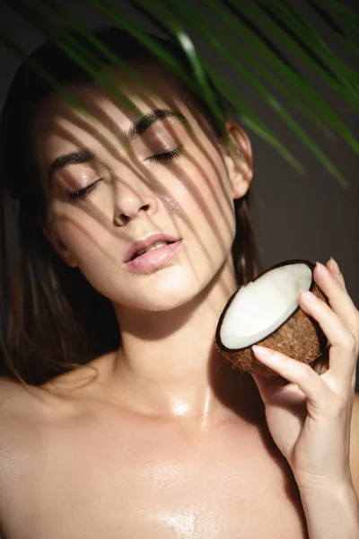 Красивая женщина с кокосом и тенями пальмового листа на лице — стоковое фото