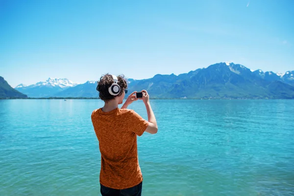 Tennager in orange t-shirt making photo of great view on smartphone. — Stock Photo, Image